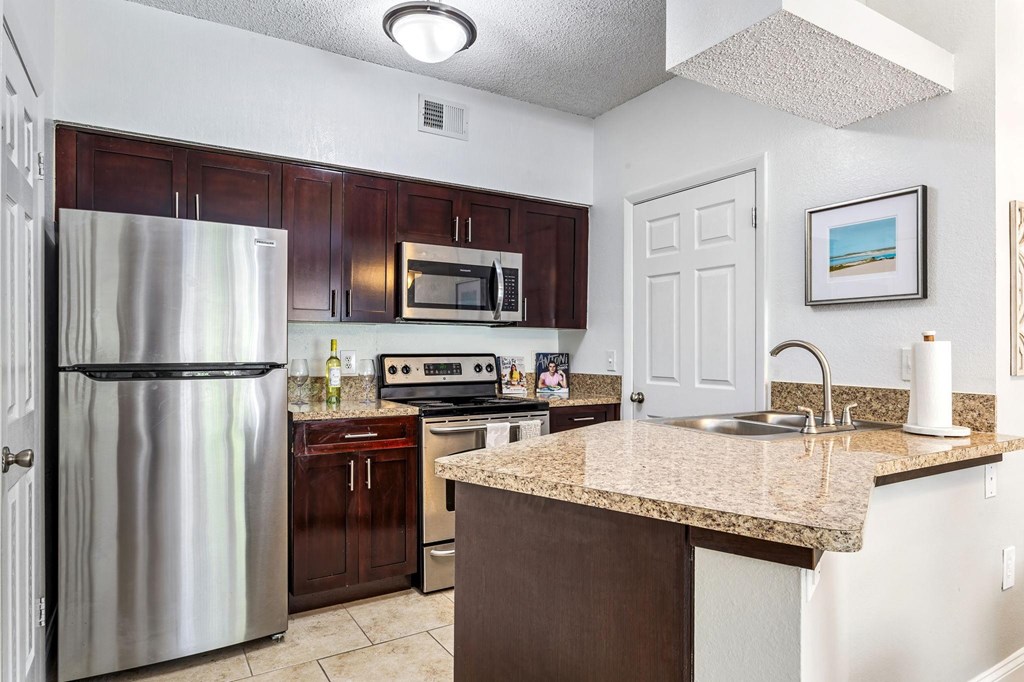 a kitchen with stainless steel appliances and a granite counter top at Waterford Park Apartment Homes, LLC, Florida