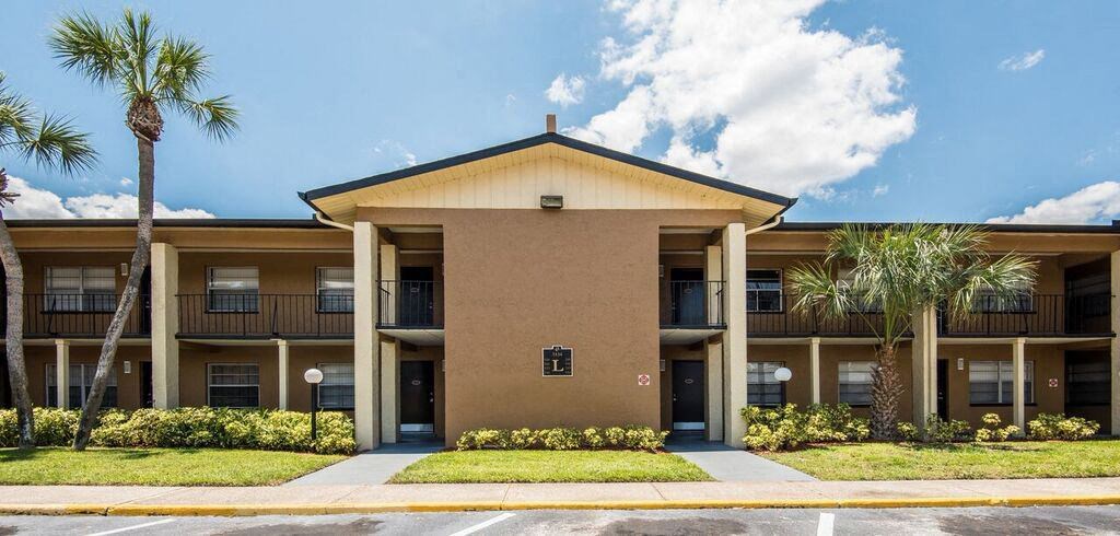 a building with palm trees in front of it at Oak Manor Apartment Homes, Tampa