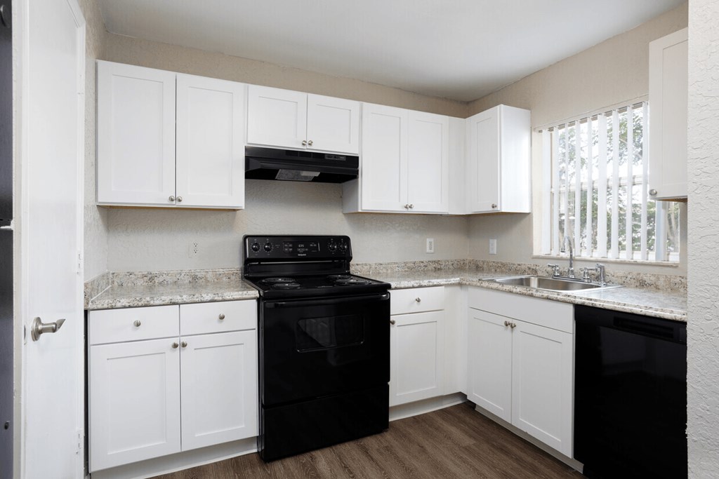 A kitchen with black appliances and white cabinets.