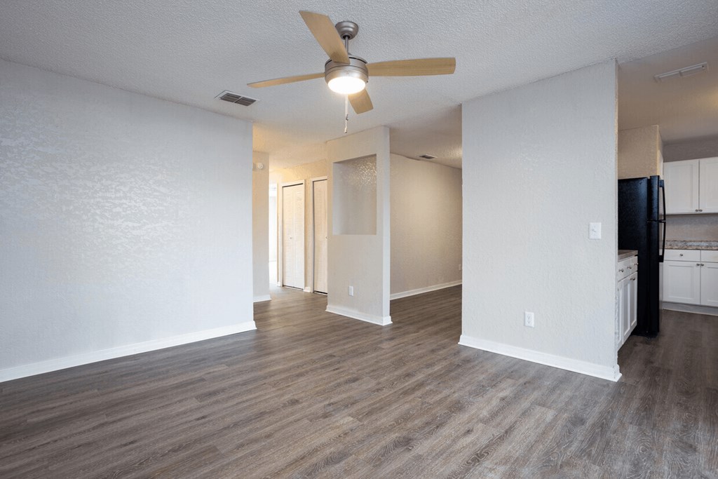 A room with a ceiling fan and wooden flooring.