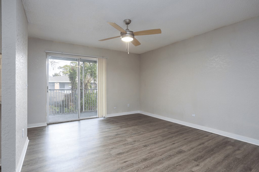 A room with a ceiling fan and sliding glass doors.