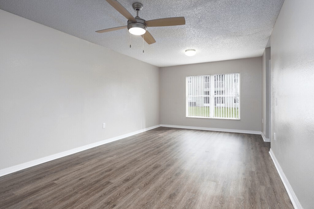 A room with a ceiling fan and wooden flooring.