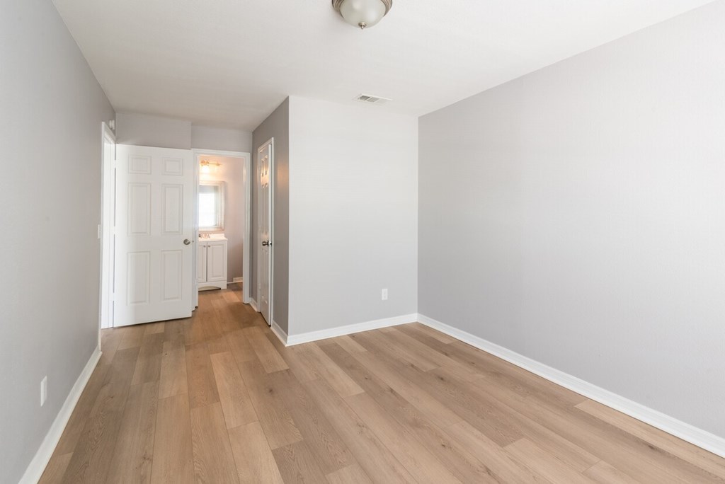 A long hallway with wood floors and white walls.