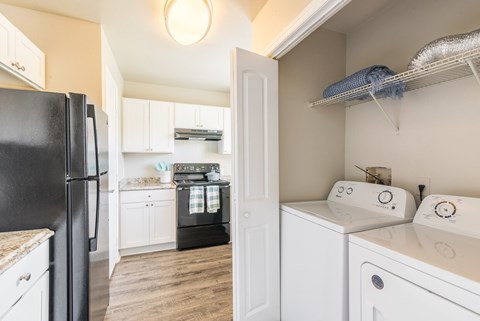 A black refrigerator is in a kitchen with white cabinets.