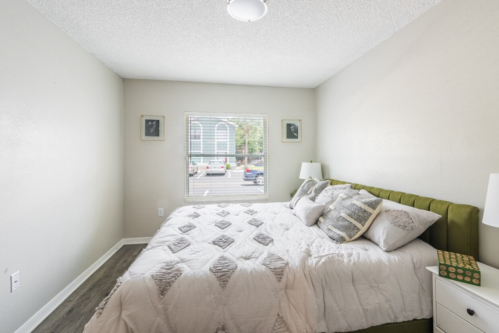 A bedroom with a large bed and a window overlooking a street.