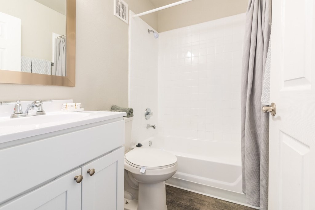 A white toilet sits in a bathroom next to a sink and a bathtub.