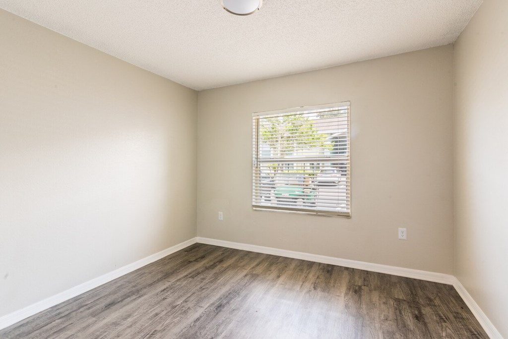 A room with a window and wooden flooring.