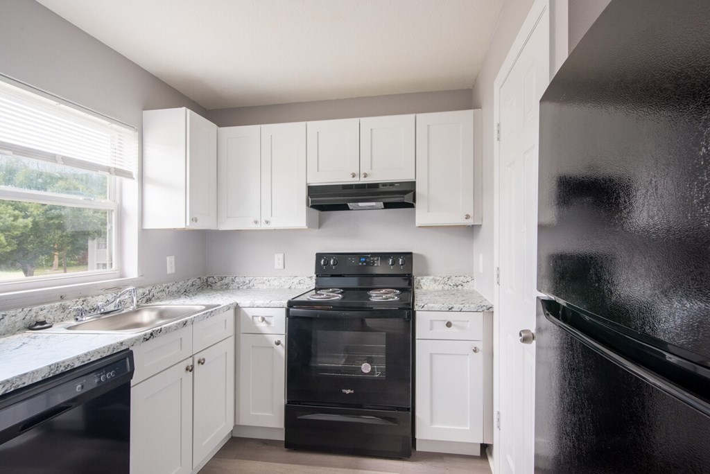 A kitchen with black appliances and white cabinets.