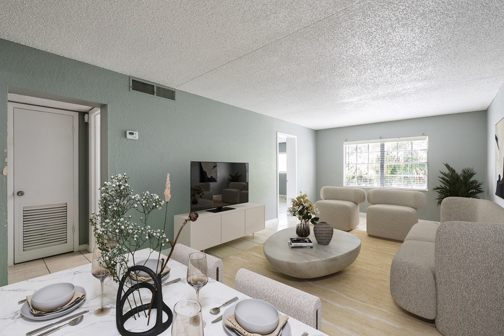 A living room with a dining table set for two and a television.