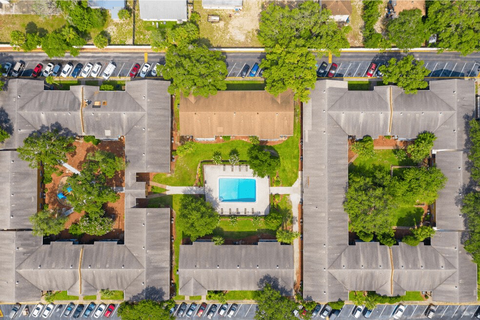An aerial view of a parking lot with a swimming pool in the middle.