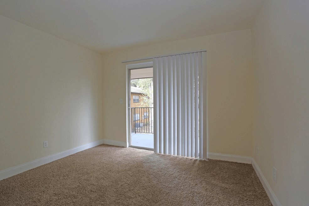 A room with a carpeted floor and a sliding glass door leading to a sizable patio or balcony.