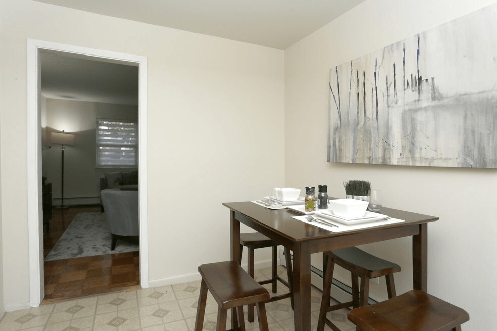 A dining room with a table set for two and a painting on the wall.