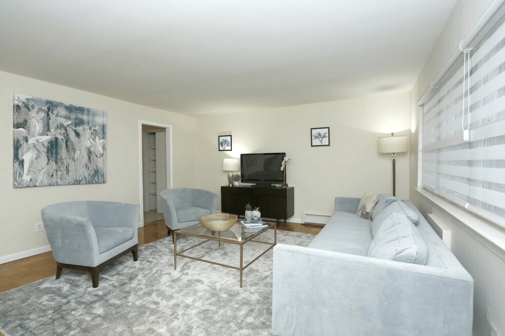 A living room with a grey couch, a coffee table, a television, and a painting on the wall.