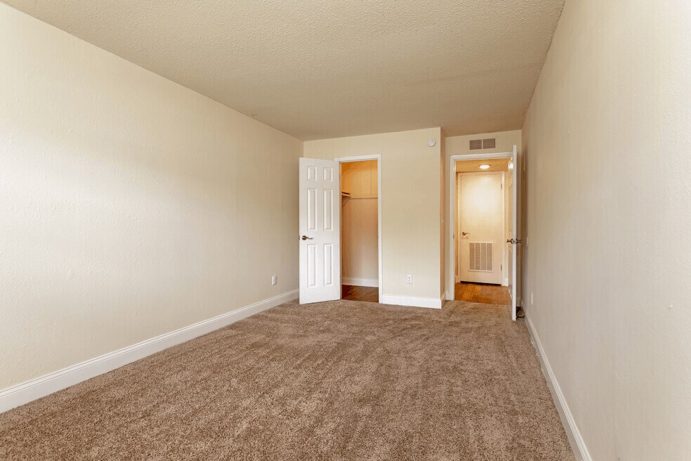 A large bedroom with beige carpeting and a walk in closet.