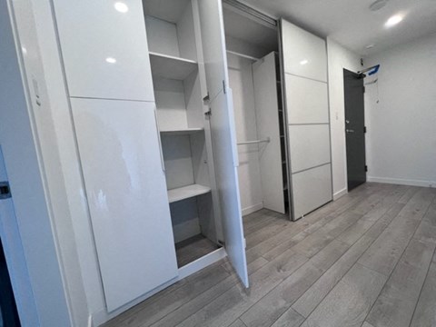 A white kitchen with a refrigerator and a door open.