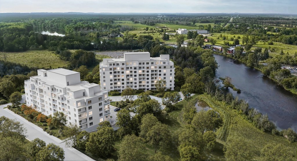 A modern white building is situated by a river in a green landscape.