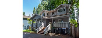 A house with a grey roof and a balcony surrounded by trees.
