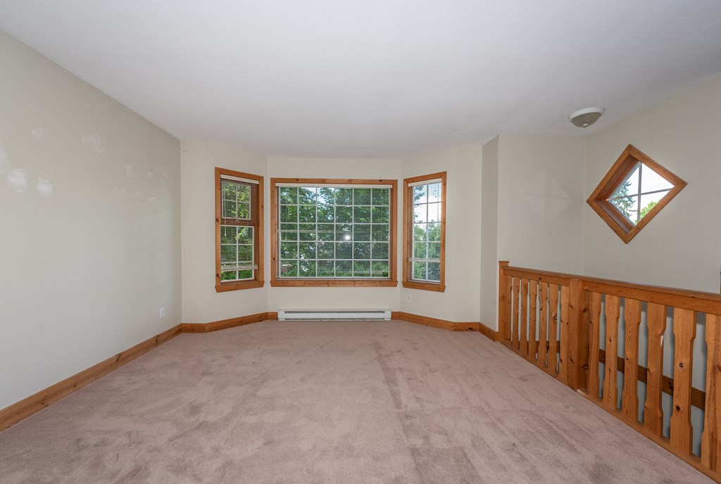 a large room with a carpeted floor and three windows