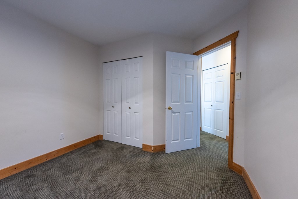 a bedroom with two doors and a carpeted floor