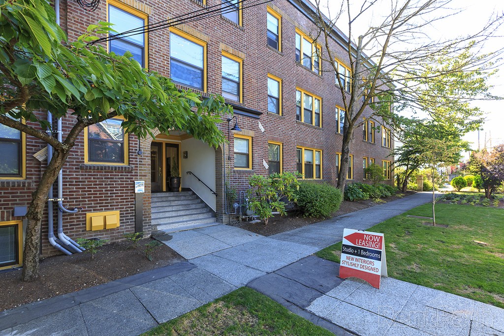 a brick building with a red ``for sale' sign in front of it