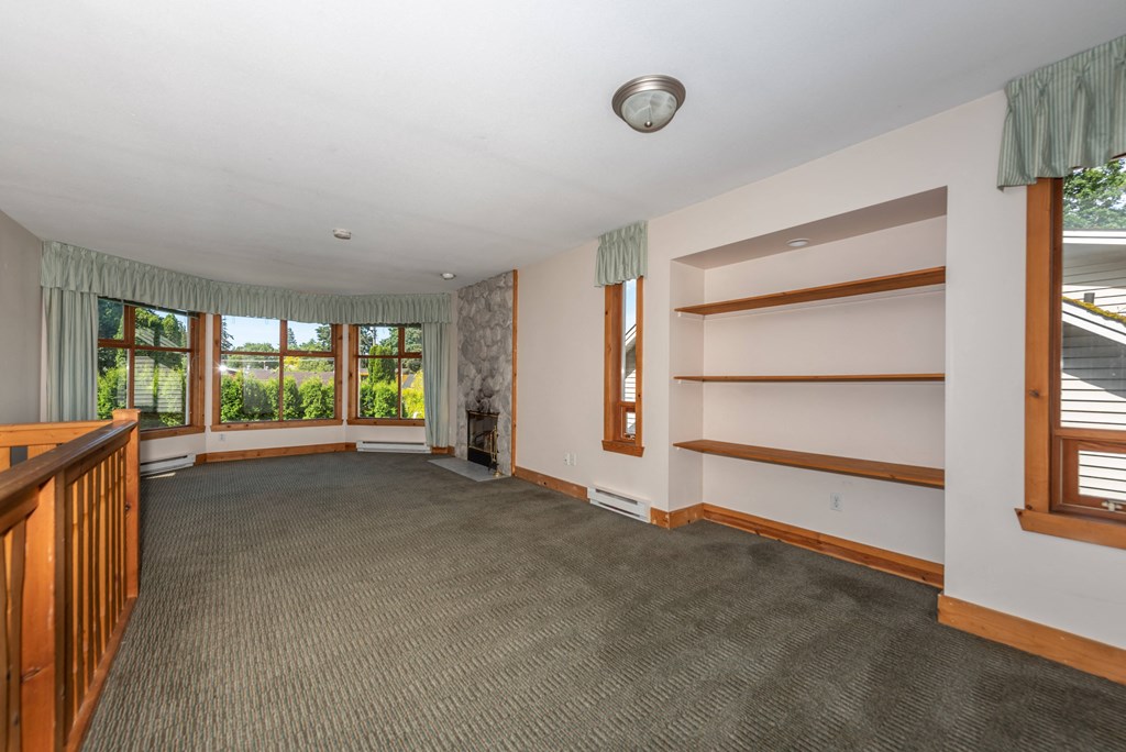 a large living room with carpeted flooring and a large window with a view of the