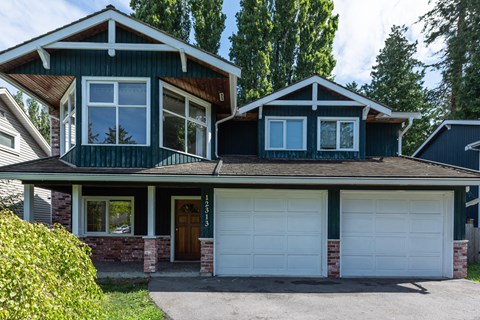 A house with a green exterior and a white garage door.