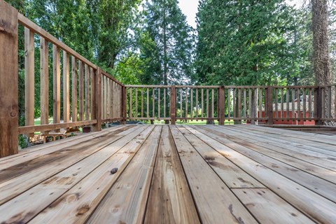 A wooden deck with a railing and trees in the background.