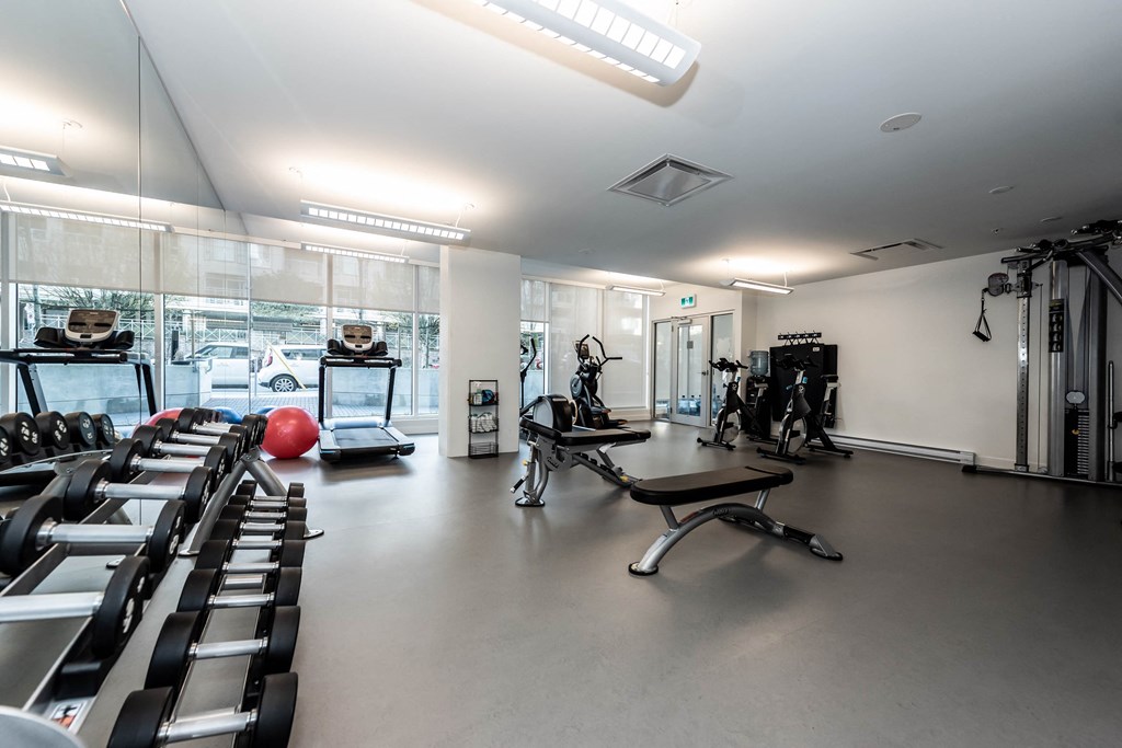 a gym with treadmills and other exercise equipment in a building with large windows