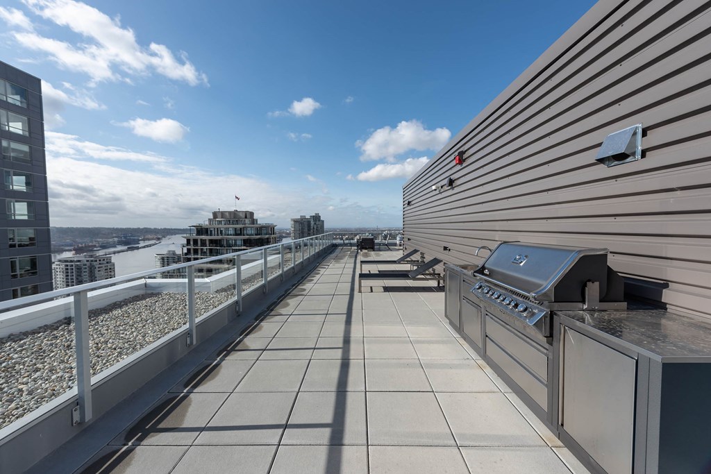 a rooftop deck with a barbecue grill and a view of the city