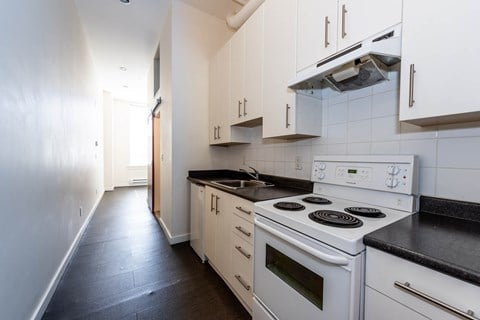 a kitchen with white appliances and white cabinets and black counter tops