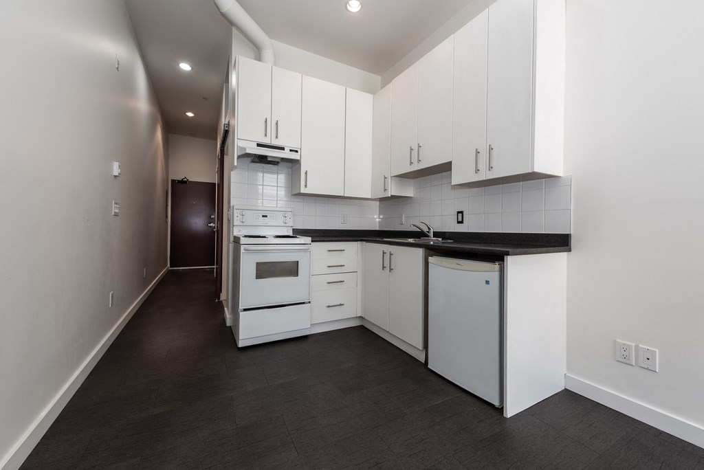 a kitchen with white cabinets and white appliances and black counter tops