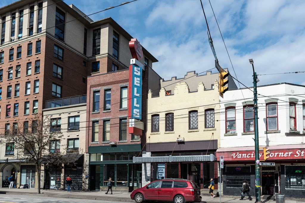 a view of a street corner with a red car parked in front of a building