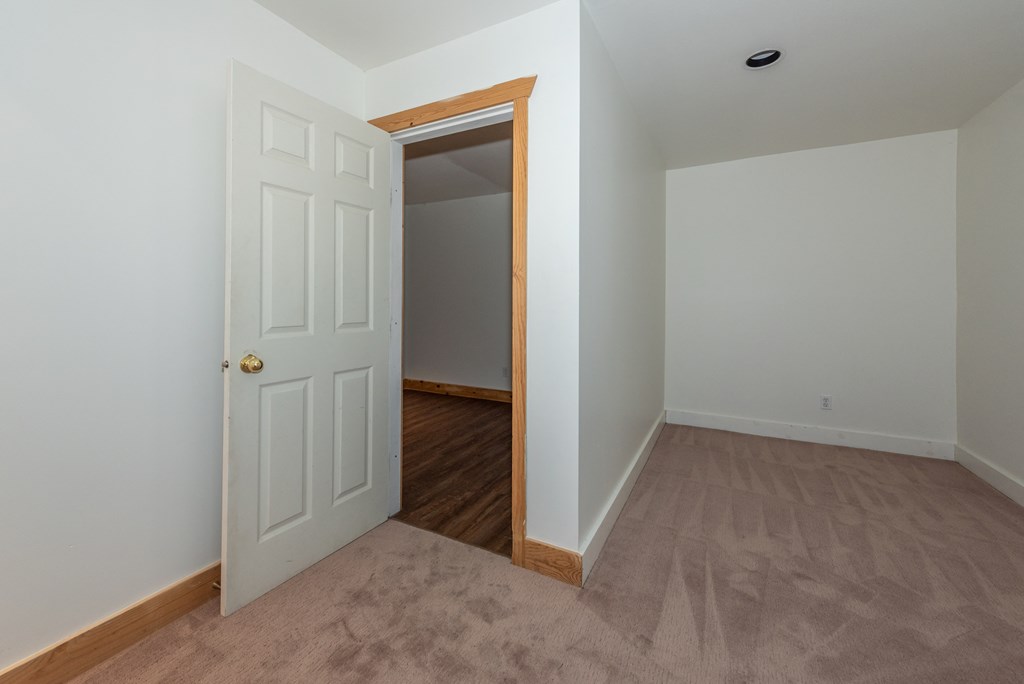 a bedroom with an open door and a carpeted floor