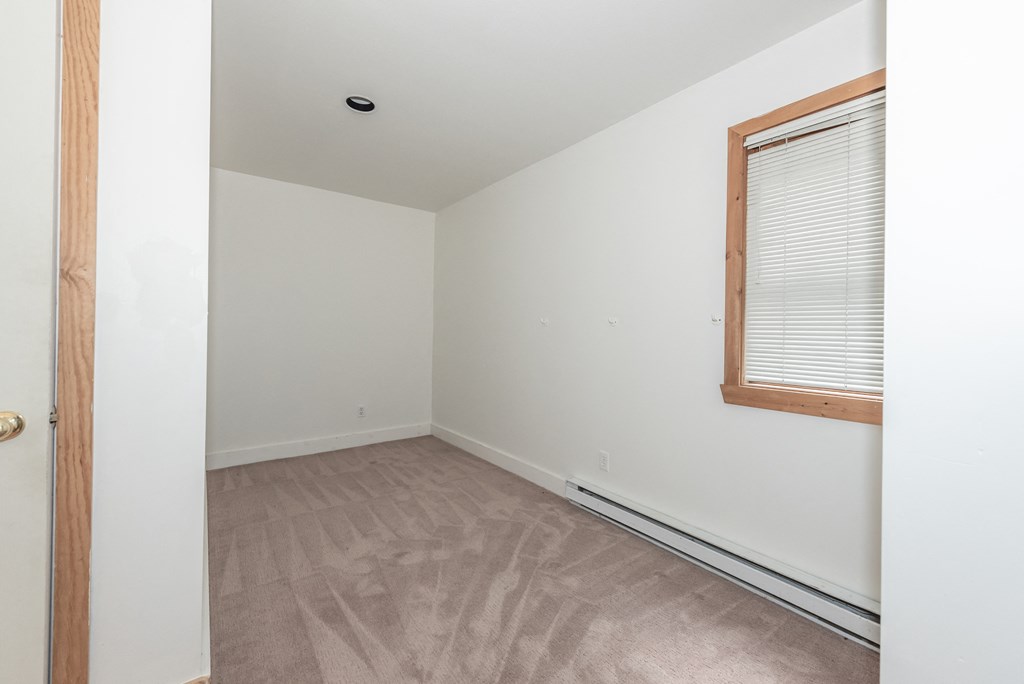 a bedroom with white walls and a wooden floor