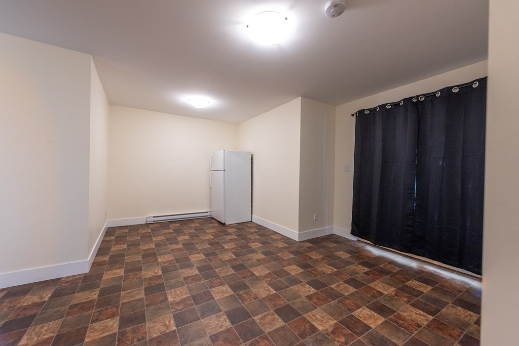 an empty room with a refrigerator in the corner