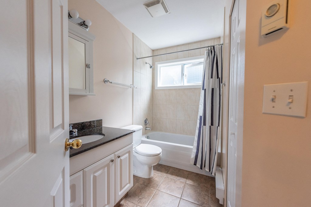 a bathroom with a white toilet next to a white bath tub