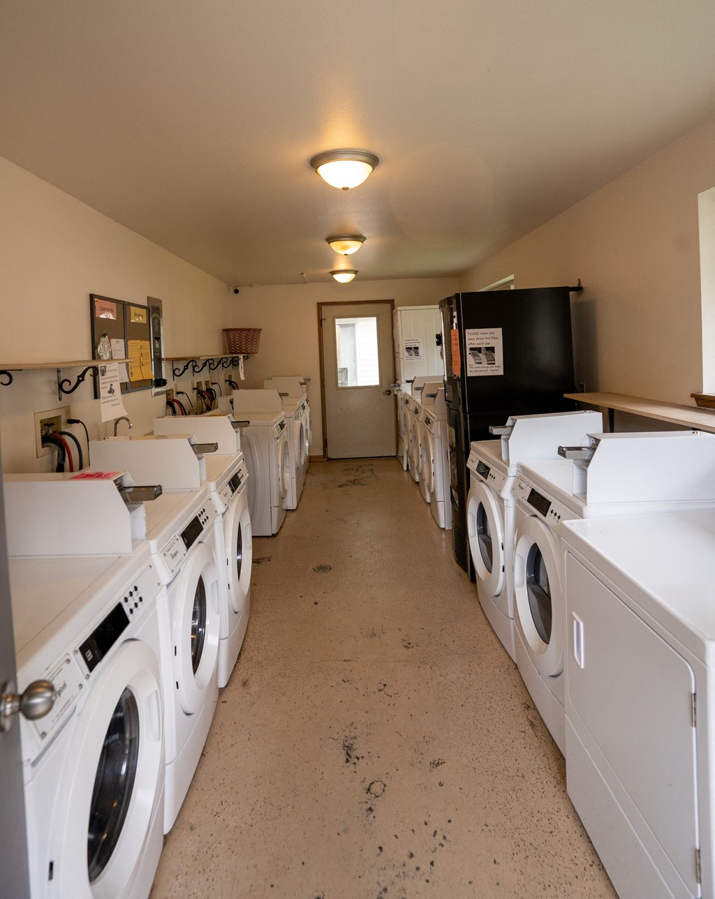 a room full of washers and dryers with a door at the end of the room