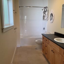 A bathroom with a toilet, sink and shower.