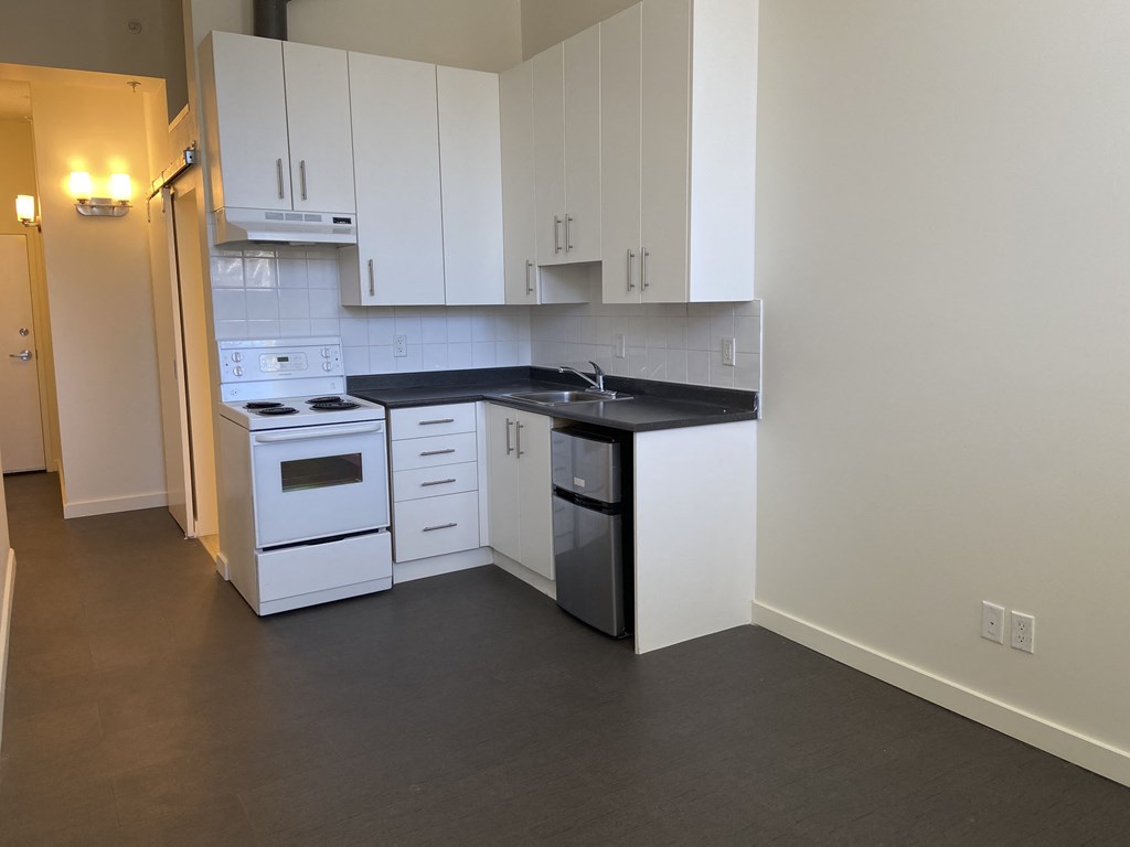 a kitchen with white cabinets and black countertops