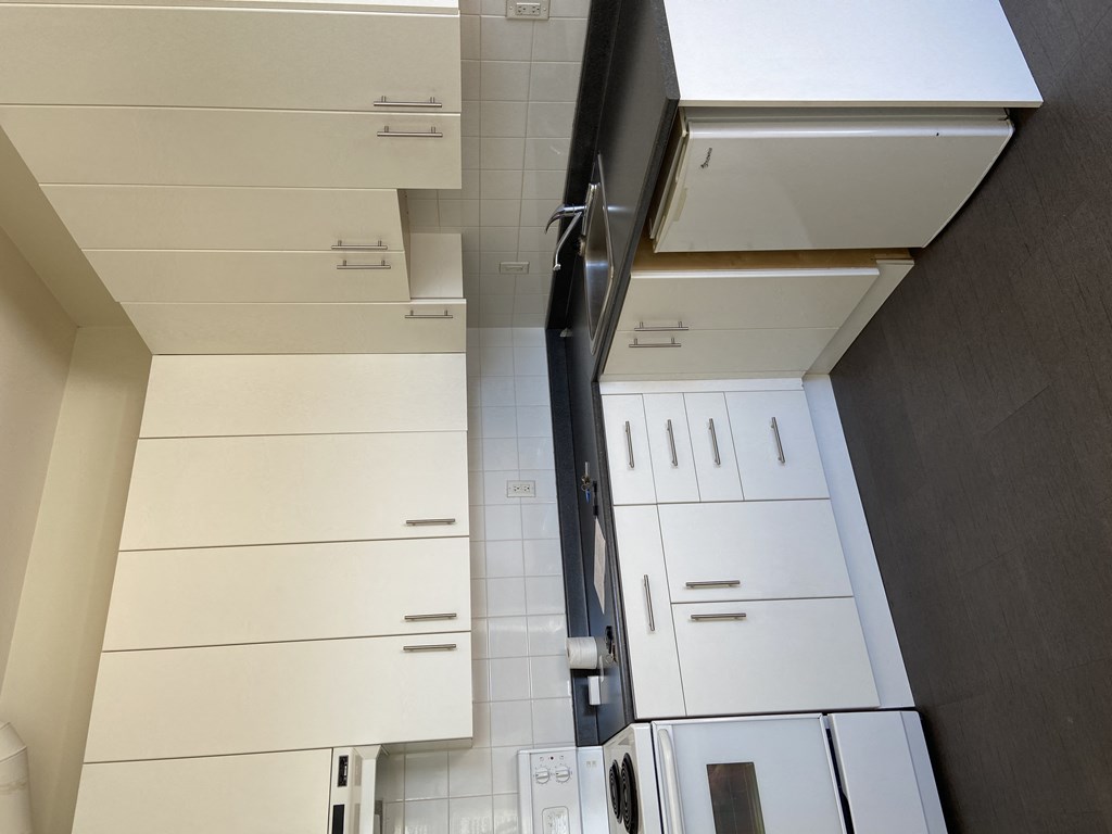 a kitchen with white cabinets and a black wall