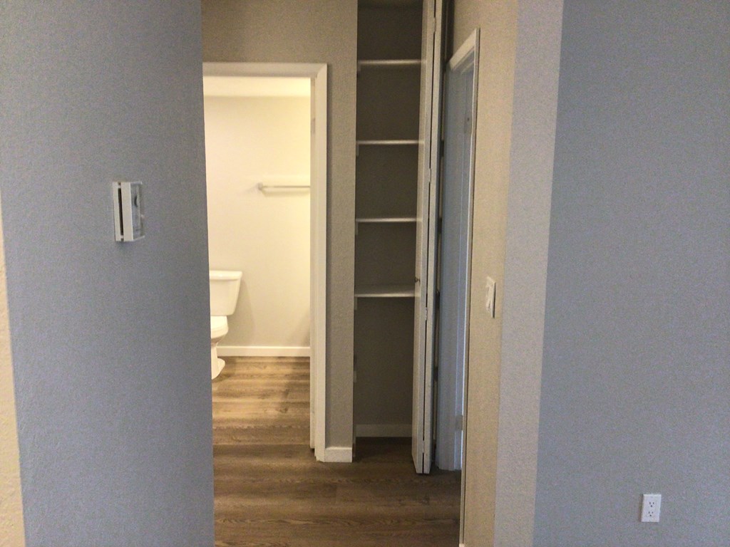 an open door leading to a bathroom with a toilet and a book shelf