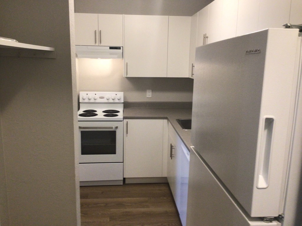 a small kitchen with white cabinets and a white stove