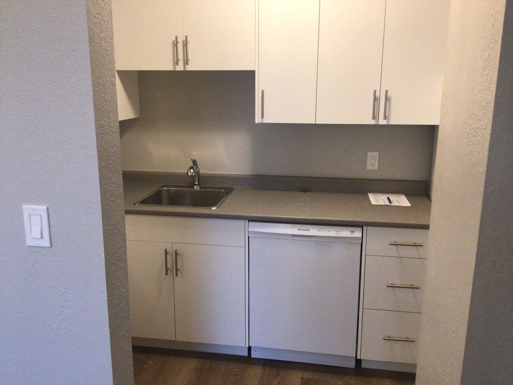 a small kitchen with white cabinets and a white dishwasher