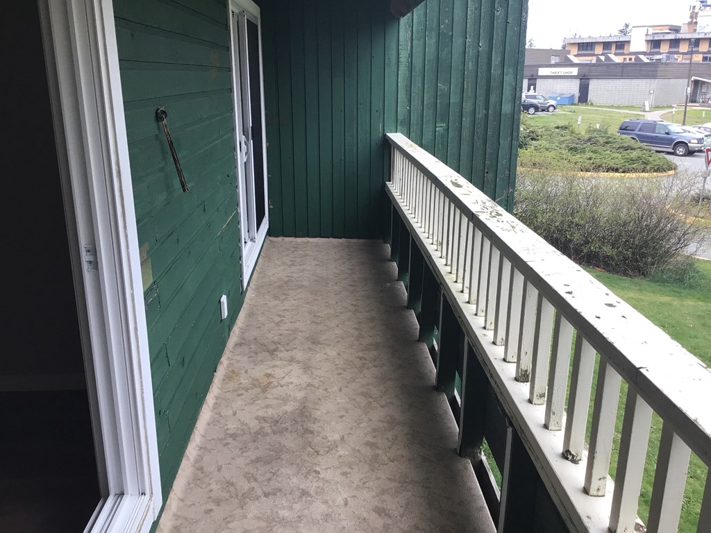 a balcony with a concrete floor and a green building in the background
