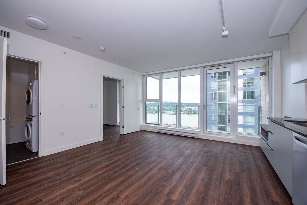 an empty living room with hardwood floors and large windows