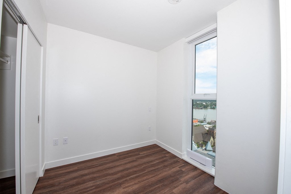 a bedroom with a large window and hardwood floors