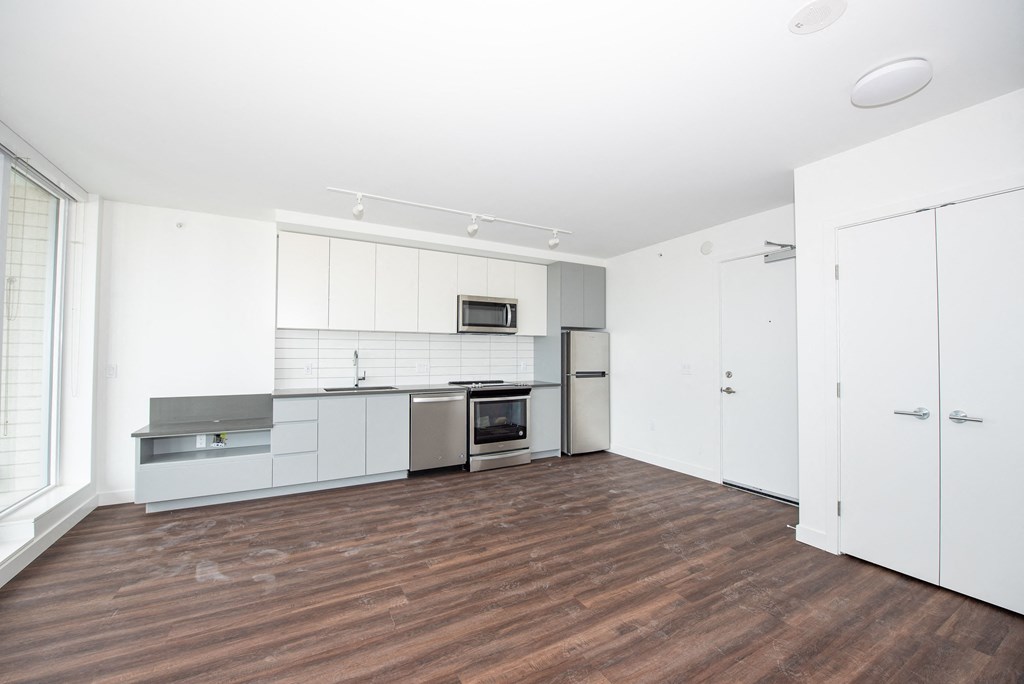 a bedroom with a medium sized white wardrobe and a kitchen with white cabinets and stainless steel appliances
