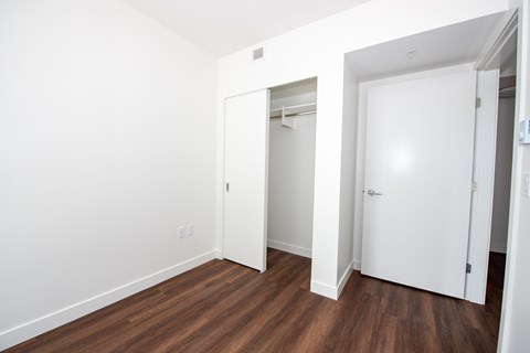 A room with a white door and a white closet with a white shelf.