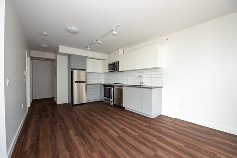 A kitchen with white cabinets and a wooden floor.