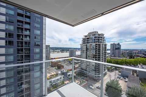 A balcony overlooks a cityscape with buildings and a cloudy sky.